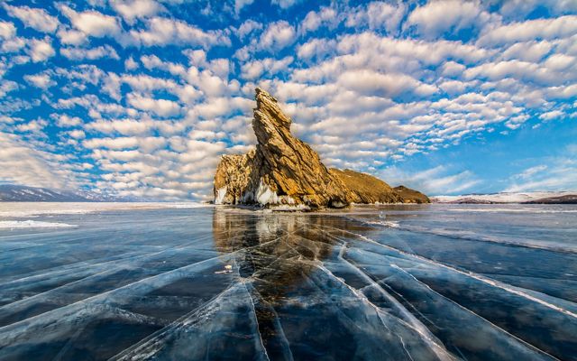 A rocky island and ice covering the surface of Lake Baikal in Russia.