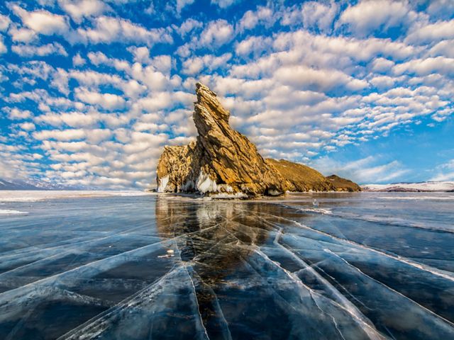 A rocky island and ice covering the surface of Lake Baikal in Russia.
