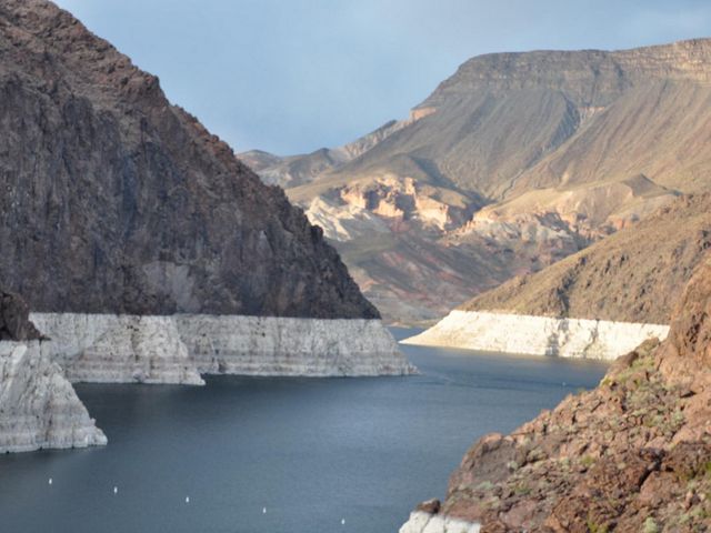 A reservoir with low water levels flows between a canyon.