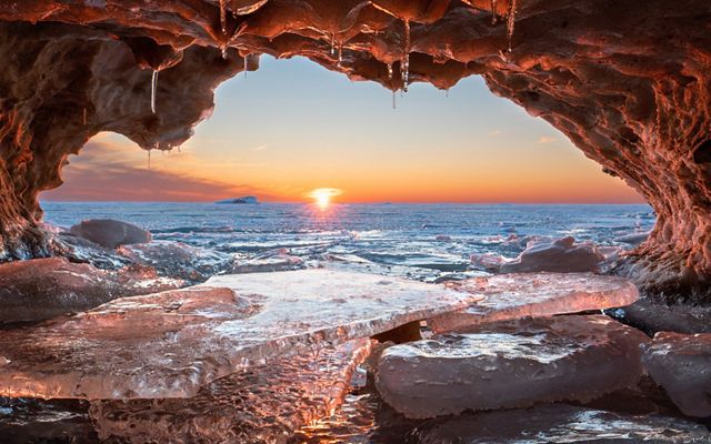 View of the low sun over Lake Michigan from inside an ice covered cave.