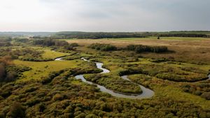 A river winds through a green valley, seen from above