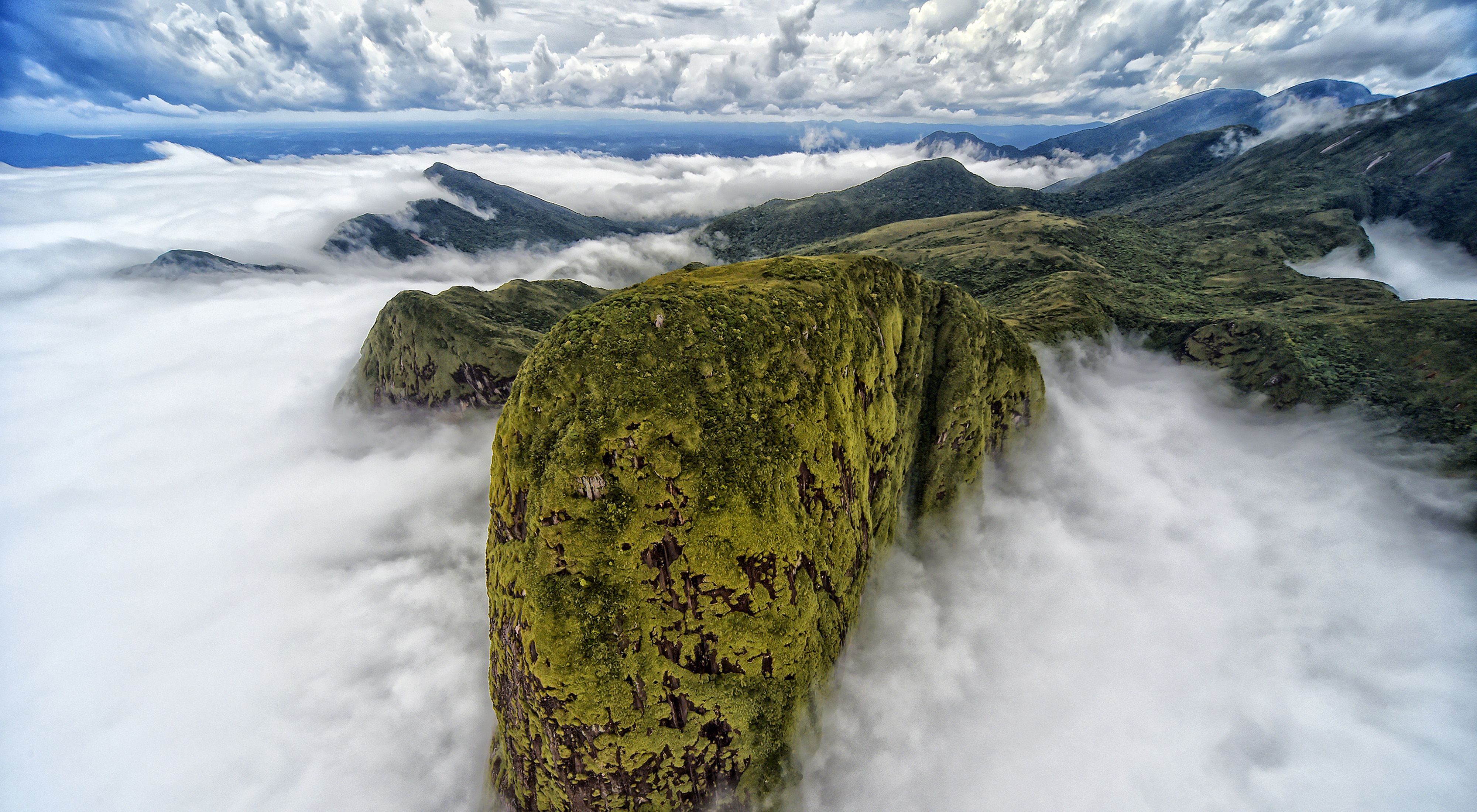 sweeping view of a green hillside amongst the clouds in Brazil