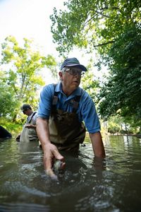 TNC's Larry Clemens thigh-deep in Fish Creek participating in a mussel survey.