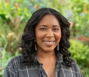 Headshot of a woman smiling in front of a green background.