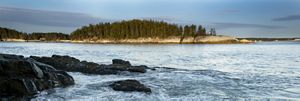 A view of the ocean and an island from a rocky shore.