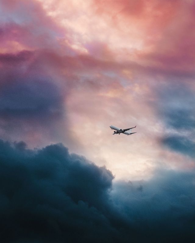A commercial airplane flies through colorful skies.