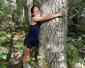 A woman hugging a very large tree.