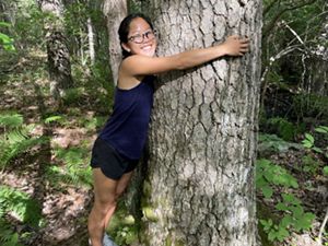 A woman hugging a very large tree.