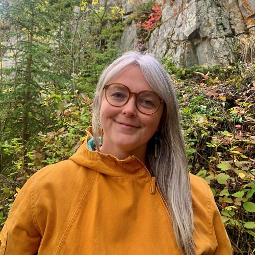 Person smiling in front of nature.