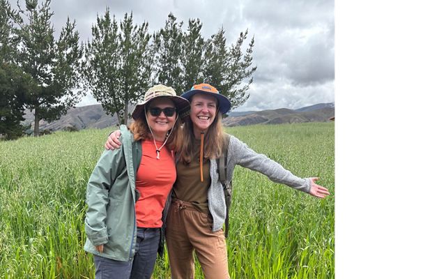 Two people standing together in a field of oats.