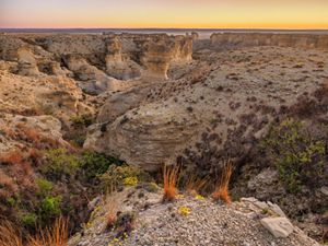 Tall chalk outcroppings and mesas cut by deep, curving valleys stretch to the distant horizon.