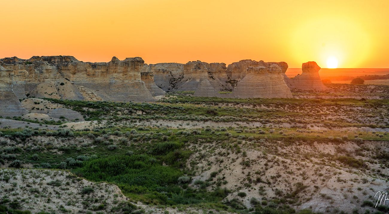 A view of Niobrara chalk formations and low scrubland from the Overlook Trail at Little Jerusalem Badlands State Park in Kansas at sunset.