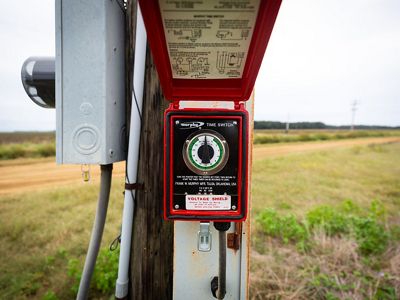 A red timer switch mounted on a pole in a field.