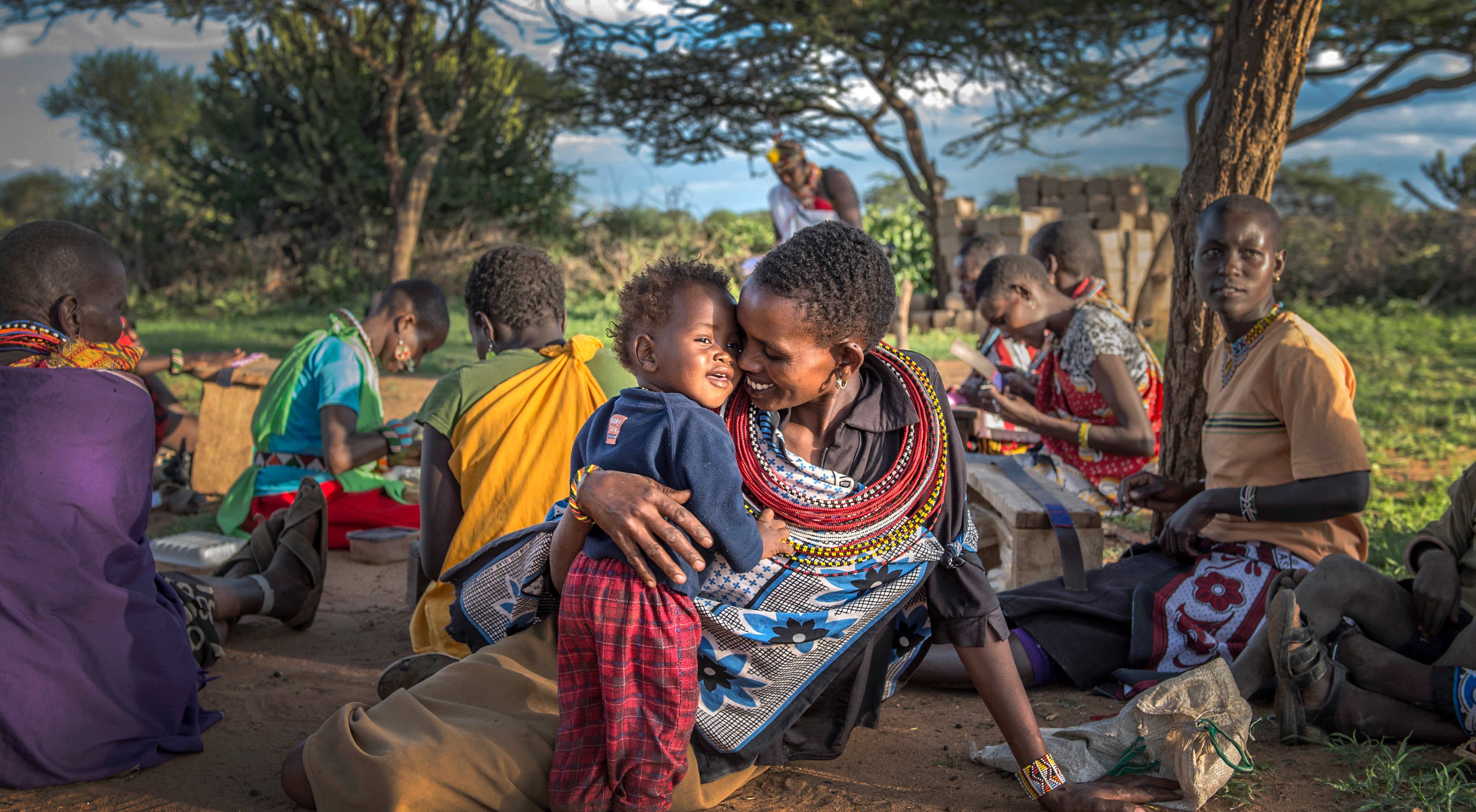 Ntipiyon Nonguta and son Bernard relax with their neighbors as they make beaded belts in Laikipia, northern Kenya. Their stunning designs are available worldwide.