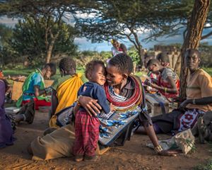 Ntipiyon Nonguta and son Bernard relax with their neighbors as they make beaded belts in Laikipia, northern Kenya. Their stunning designs are available worldwide.