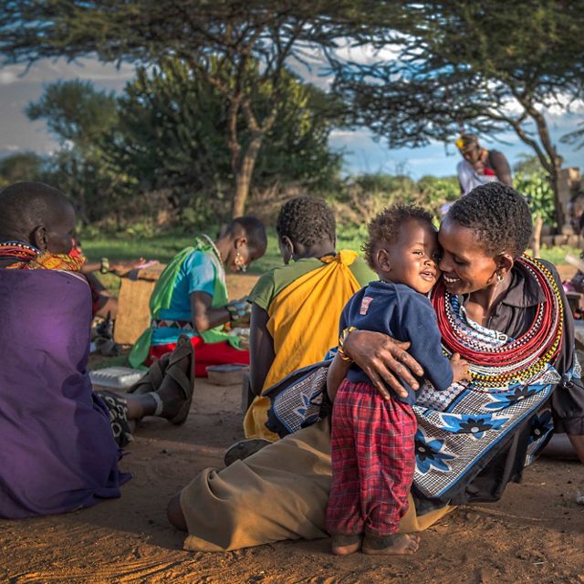 Ntipiyon Nonguta and her son Bernard relax with their neighbors as they make beaded belts for Loisaba Community Trust in northern Kenya to be sold to international markets.