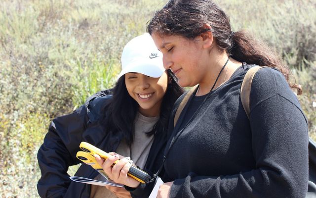 Two high school students look at a GPS on Dangermond Preserve in California.