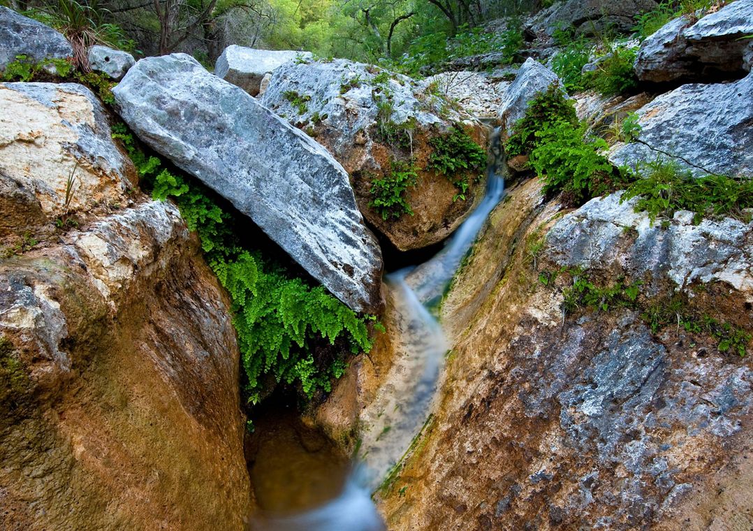 Water trickles over limestone boulders covered in moss.