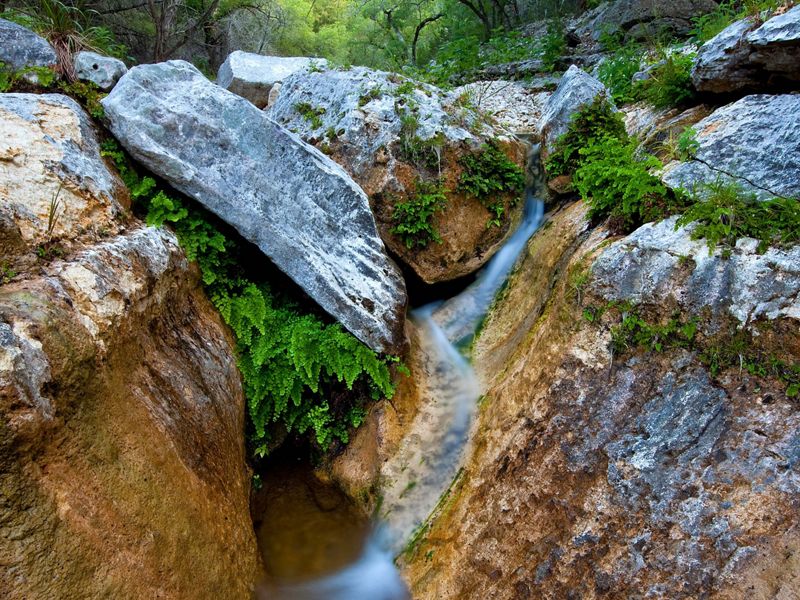 Water trickles over limestone boulders covered in moss.