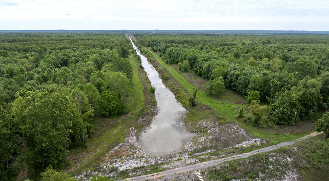 A dense forest surrounds a structure of water and concrete.