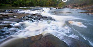 Rough river waters flow over big rocks.