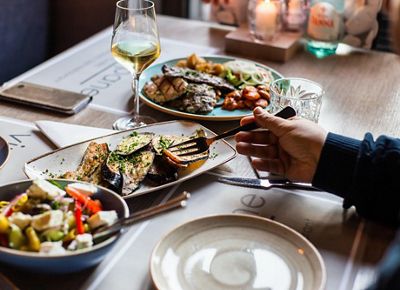 a person's hand pictured at a dinner table with a variety of food.