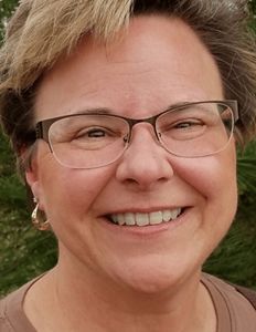 Headshot of LuAnn Creighton wearing glasses and gold hoops. 