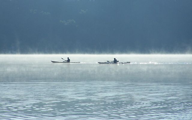 Mist rises from the waters of Lulu Lake as two kayakers paddle by.
