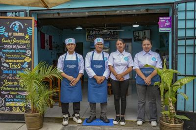 Cuatro personas con uniforme culinario posan en la puerta de un restaurante colorido.