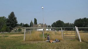 Mujer arrodillada sobre el pasto instalando una ARU sobre un poste.