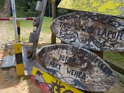 Cartelería a la entrada del bosque Wehea hechos sobre troncos tallados por la comunidad.