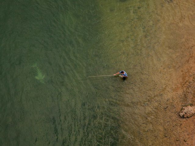 Boto do Araguaia (Inia araguaiaensis) nadando junto a un pescador local usando una caña de bambú para pescar en el río Tocantins, en Imperatriz-MA