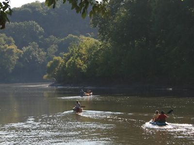 Tres canoas con personas en ellas remando cuesta abajo de un río.
