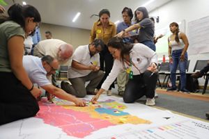 grupo de personas en el suelo poniendo notas sobre un mapa trabajando en una planificación rural.