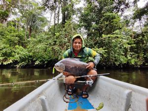 Um homem em uma embarcação segura com orgulho um grande peixe, exibindo sua captura durante uma jornada de pesca.