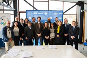  Un grupo de cinco personas se reunió alrededor de una mesa para discutir documentos y compartir ideas en un entorno colaborativo.