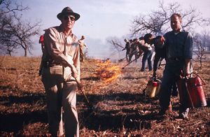 Trabajadores realizando quema controlada en una pradera.