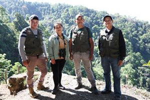 4 personas posan frente a un paisaje boscoso.