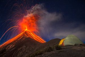 A lush forested moutain rises into the clouds in southe