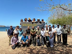 Personas posan para foto grupal en una playa.