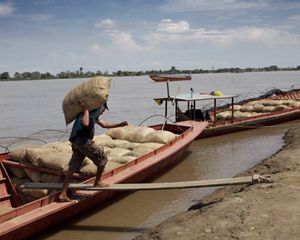 Un hombre descarga mercancías desde su bote en el río Magdalena en Colombia.