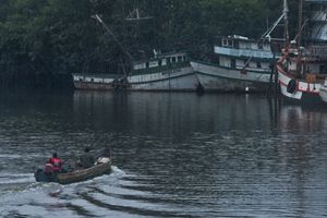 Una embarcación con varias personas a bordo se desliza sobre una superficie de agua tranquila bajo un cielo azul despejado.