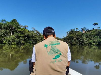 Hombre de espaldas del equipo TNC navegando en canoa por el Rio Caquetá.