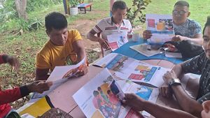 personas sentadas alreadedor de una mesa viendo documentos y sistematizando información.