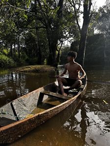 Young man in bathsuit in a traditional boat. 