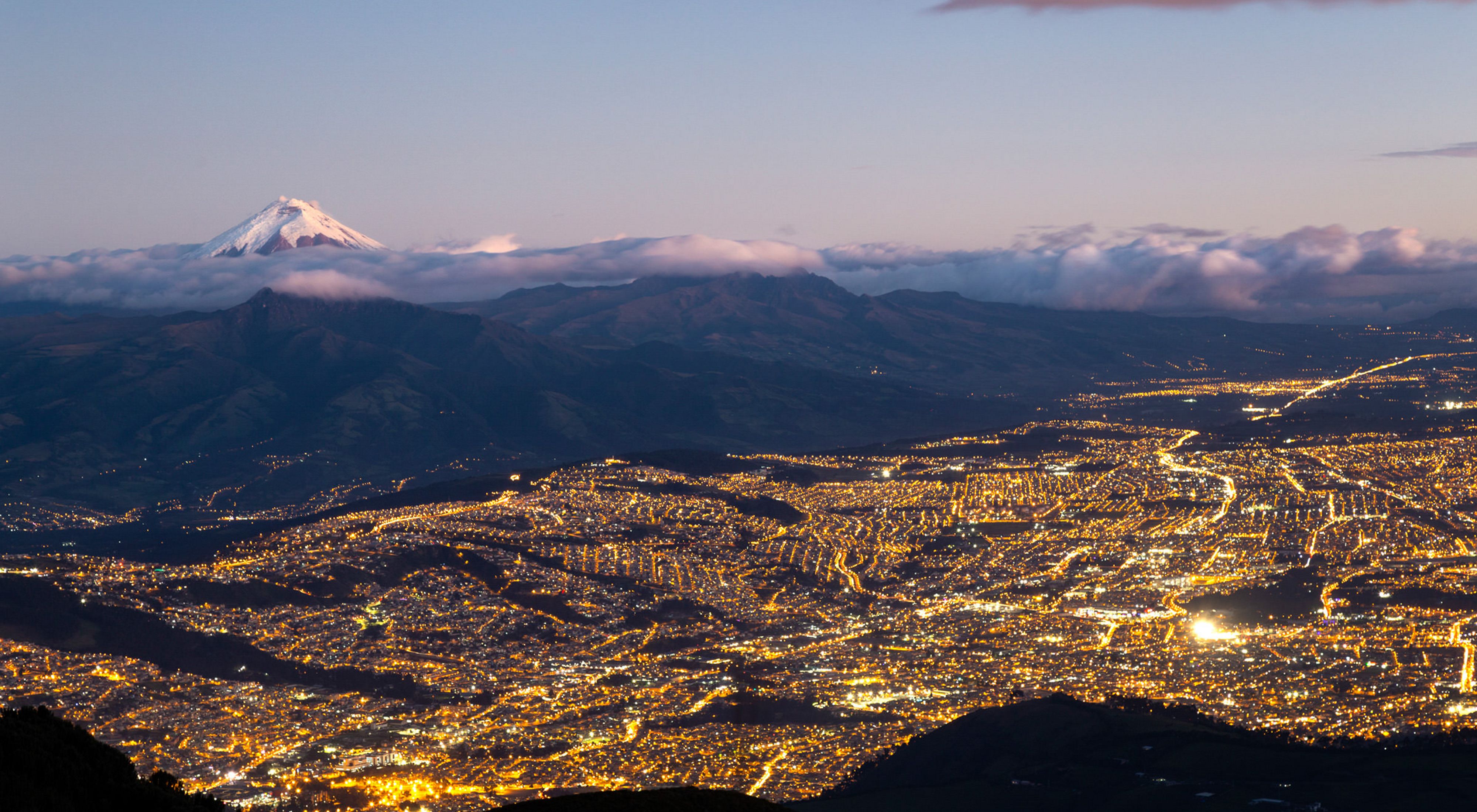 Quito at night with the Chimborazo snowpeak in the background. 