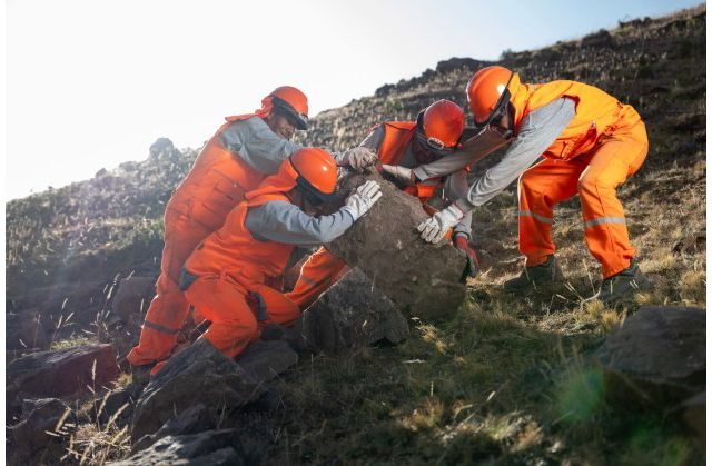 Trabajadores cargando rocas pesadas en la montaña.