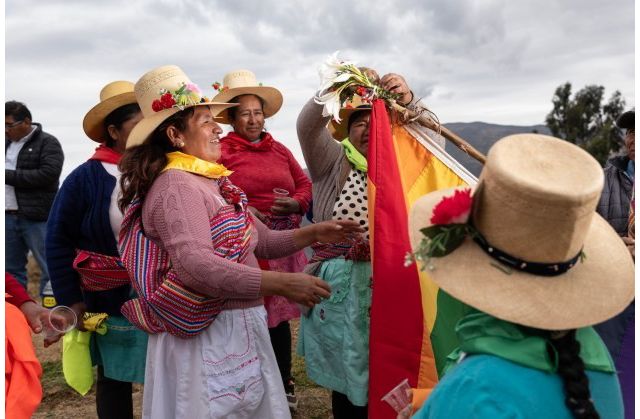 Mujeres de vestido multicolor y sombreros en festejo.