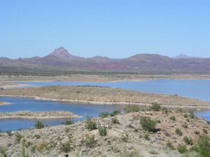 Vista panorámica de curso de agua entre planicies y montañas.