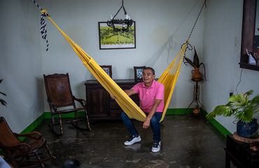 Un hombre con una camisa rosa posa en una hamaca.